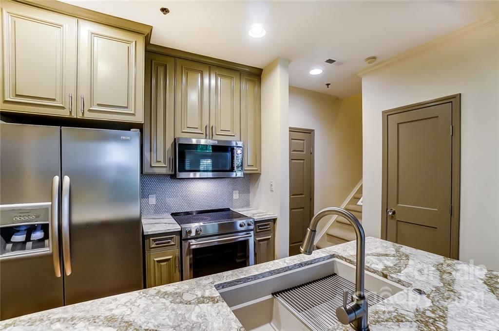 416 Queens Road, Unit 14 Charlotte, NC 28207 - Photo 4 of 27 a kitchen with stainless steel appliances granite countertop a refrigerator a stove and a sink with wooden floor