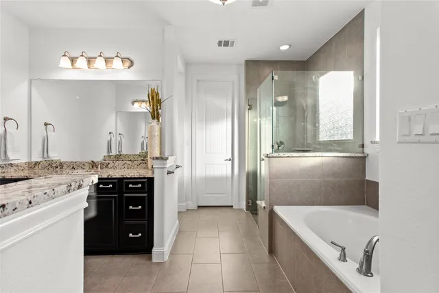 a bathroom with a granite countertop tub sink and mirror