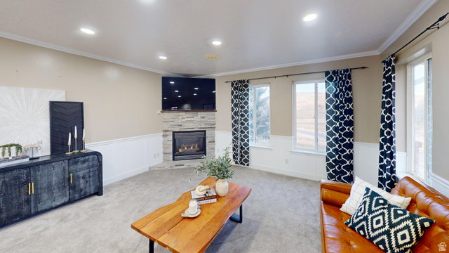 9029 North Treasureton Road Preston, ID 83263 - Photo 4 of 31 Carpeted living room featuring a wainscoted wall, ornamental molding, a stone fireplace, recessed lighting, and a decorative wall