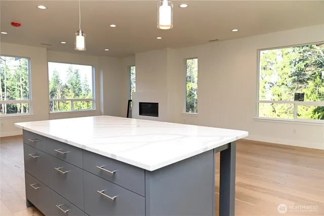 a room with kitchen island a sink wooden floor and a large window