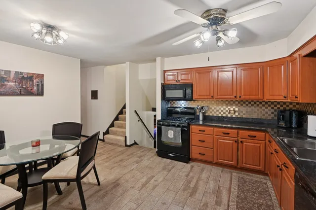 a kitchen with stainless steel appliances granite countertop a stove top oven a sink dishwasher a dining table and chairs with wooden floor