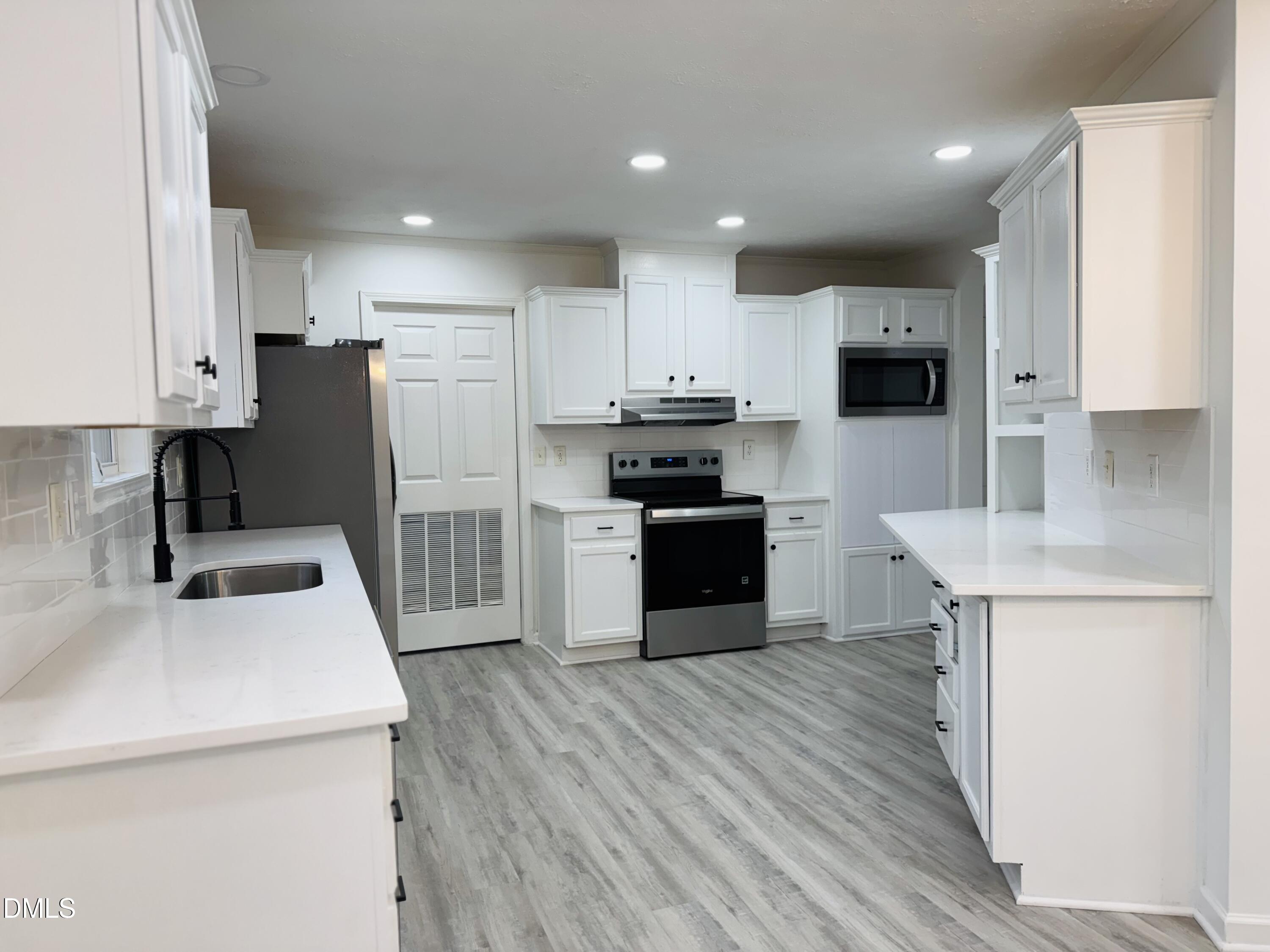 73 Christys Way Roxboro, NC 27574 - Photo 4 of 13 a kitchen with kitchen island white cabinets appliances and wooden floor