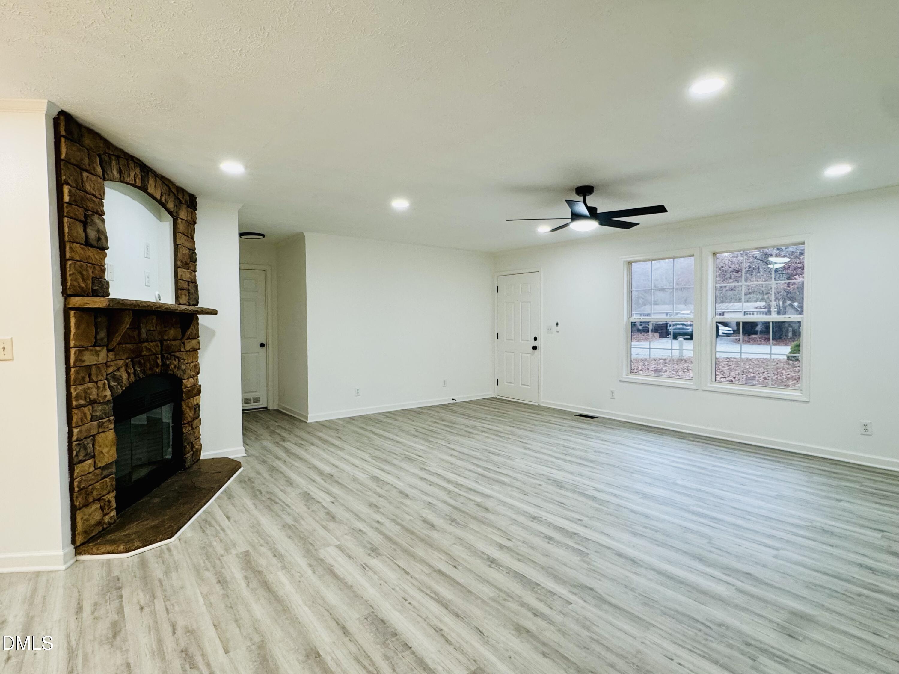73 Christys Way Roxboro, NC 27574 - Photo 7 of 13 an empty room with wooden floor a fireplace and windows