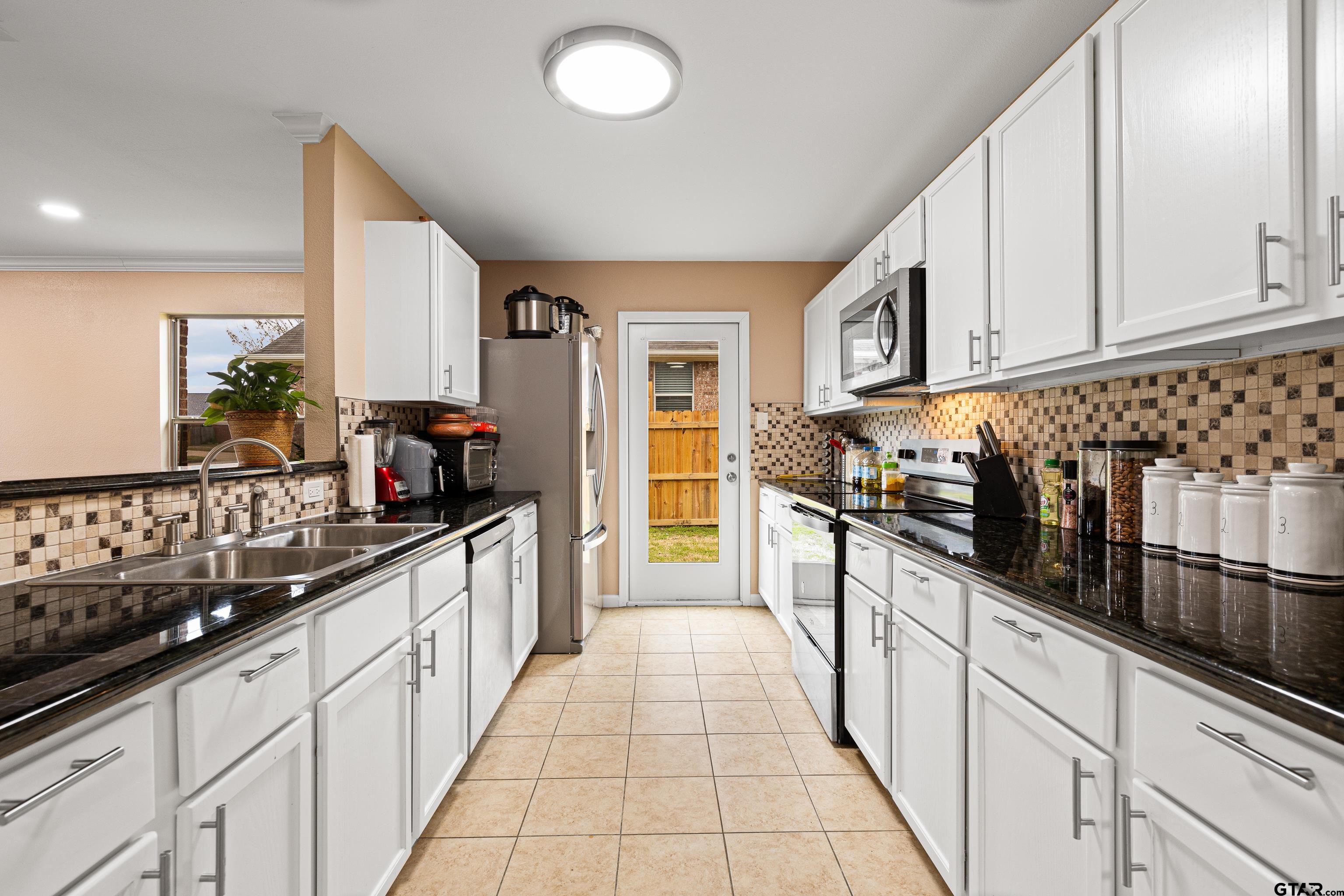 553 Princess Place Tyler, TX 75704 - Photo 25 of 32 a large white kitchen with stainless steel appliances granite countertop a sink and cabinets