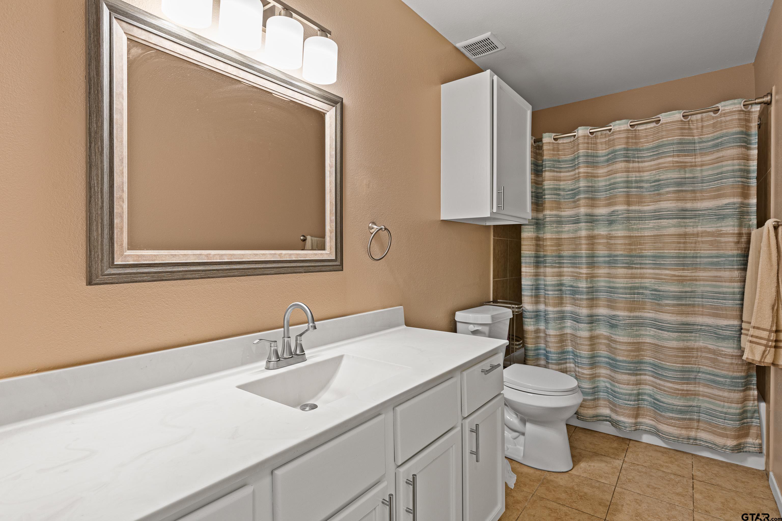 553 Princess Place Tyler, TX 75704 - Photo 30 of 32 a bathroom with a toilet a sink and mirror