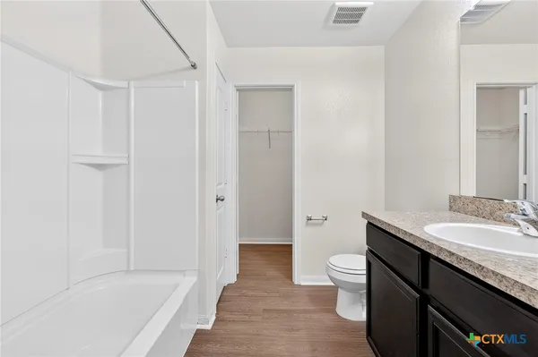 a bathroom with a granite countertop sink a toilet and shower