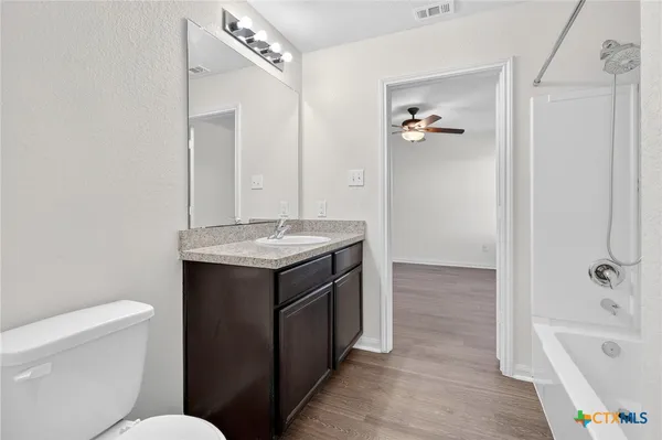 a bathroom with a granite countertop sink a toilet a mirror a vanity and bathtub