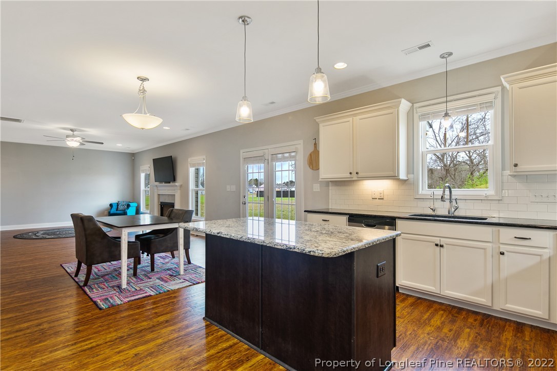 5213 Bree Bridge Road Hope Mills, NC 28348 - Photo 21 of 50 a kitchen with stainless steel appliances granite countertop a stove a sink dishwasher and a dining table with wooden floor