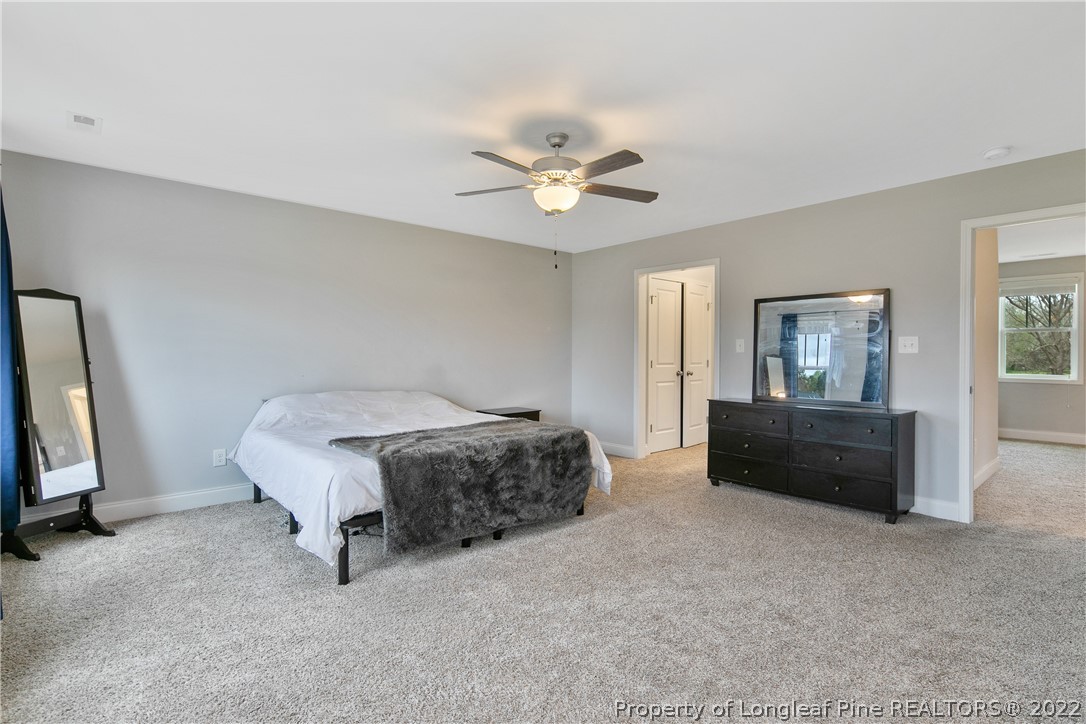 5213 Bree Bridge Road Hope Mills, NC 28348 - Photo 28 of 50 a spacious bedroom with a bed and a chandelier