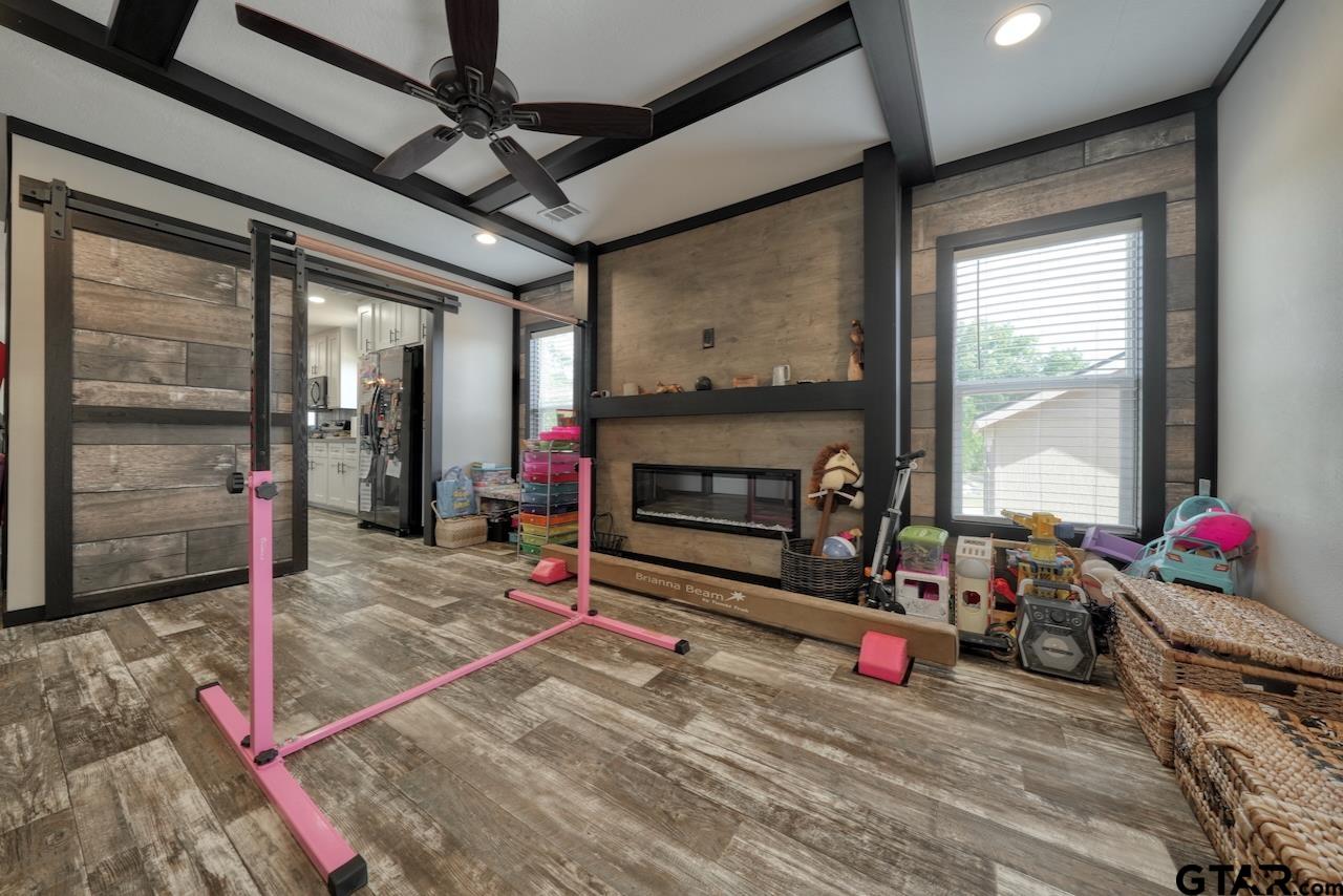 17675 Pine Drive Lindale, TX 75771 - Photo 16 of 35 a living room with furniture a flat screen tv and a floor to ceiling window