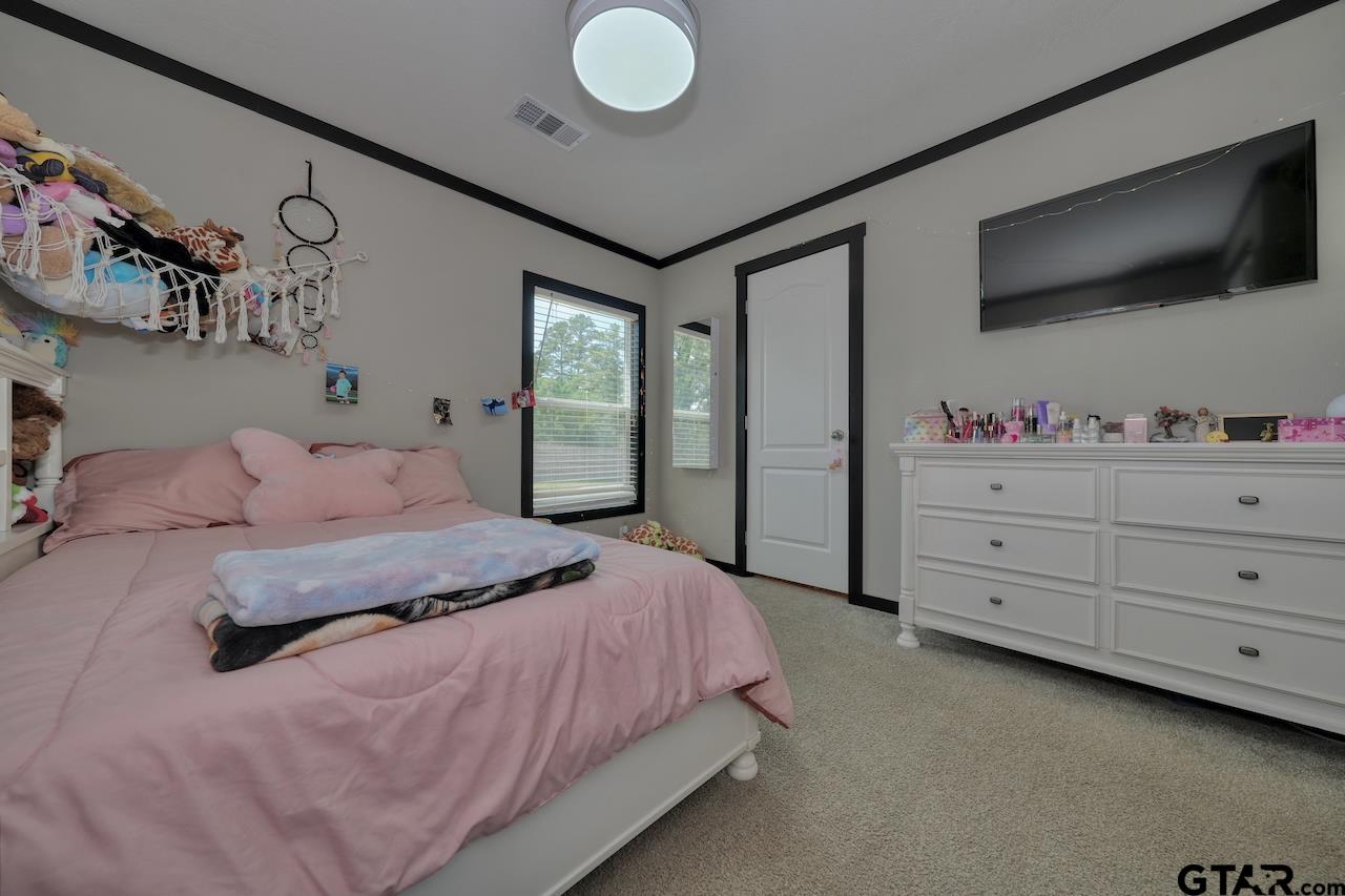 17675 Pine Drive Lindale, TX 75771 - Photo 23 of 35 a bedroom with a large bed and a flat tv screen on dresser