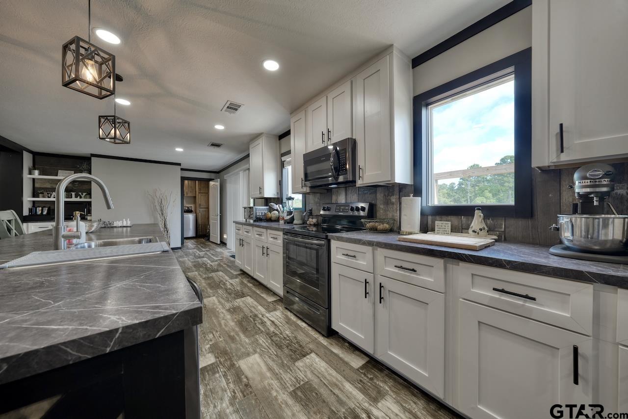 17675 Pine Drive Lindale, TX 75771 - Photo 7 of 35 a kitchen with kitchen island granite countertop a sink appliances cabinets and a counter top space
