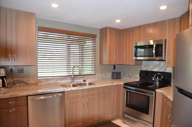 a kitchen with granite countertop a sink cabinets and stainless steel appliances
