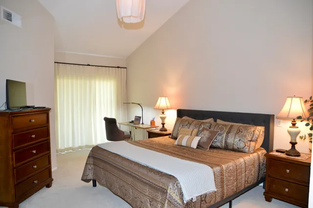 a bedroom with a bed and a flat tv screen on dresser