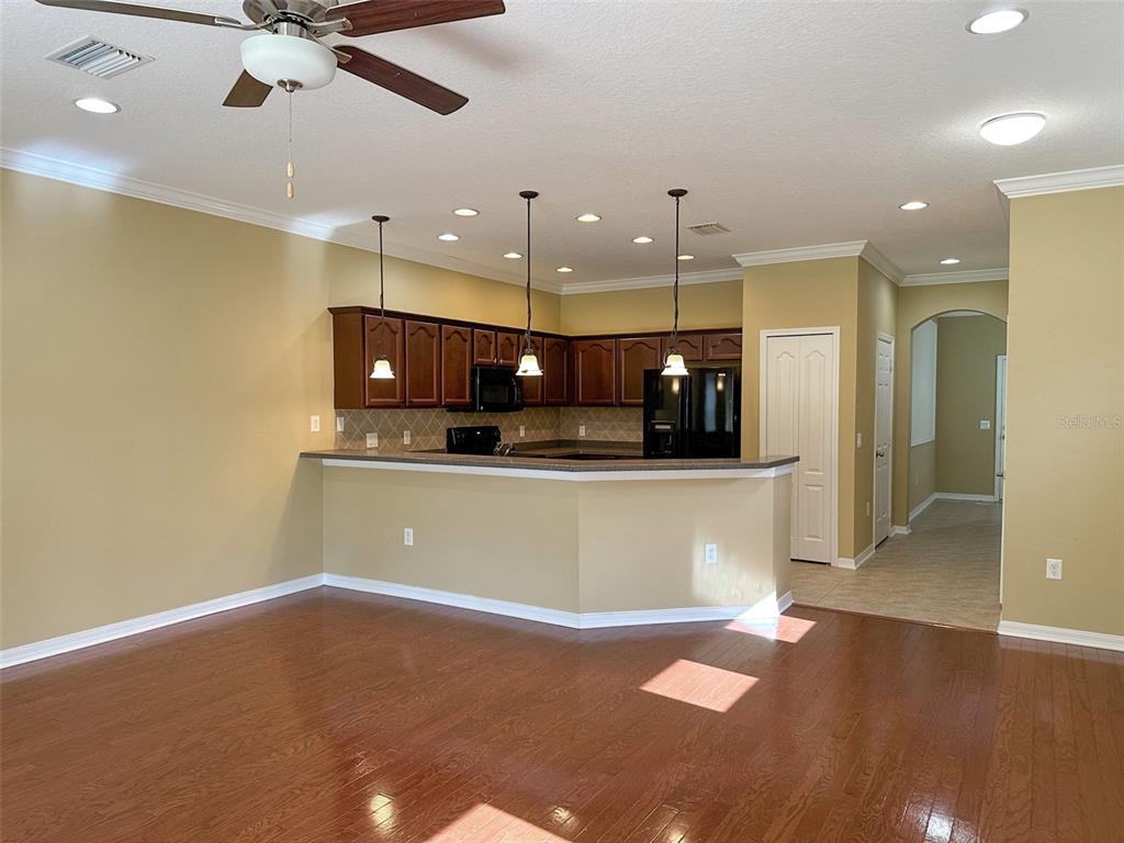 11801 Essington Street New Port Richey, FL 34654 - Photo 5 of 79 a view of an empty room with kitchen and ceiling fan