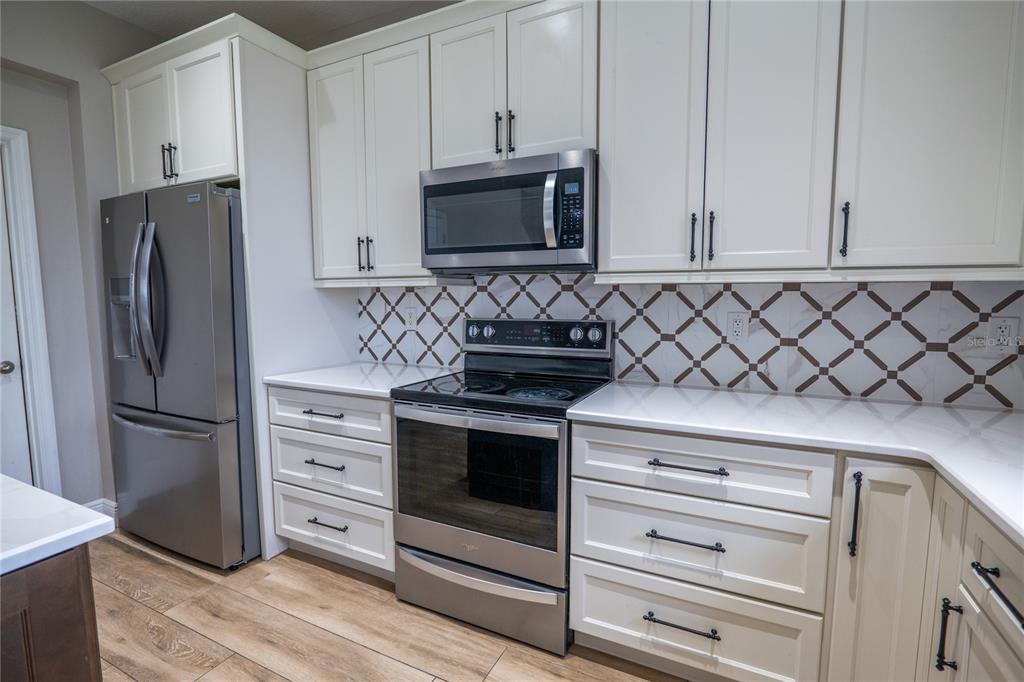 852 North Jacks Lake Road Clermont, FL 34711 - Photo 11 of 29 a kitchen with granite countertop white cabinets and stainless steel appliances