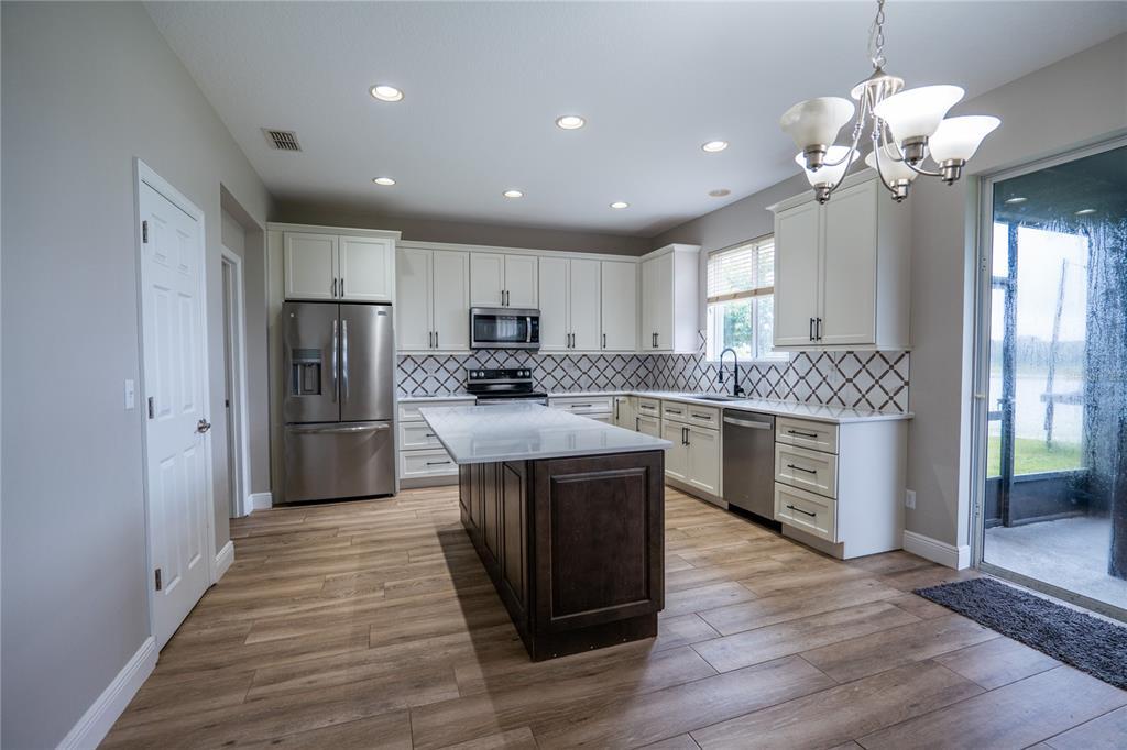 852 North Jacks Lake Road Clermont, FL 34711 - Photo 8 of 29 a kitchen with kitchen island granite countertop stainless steel appliances cabinets a sink and a counter top space