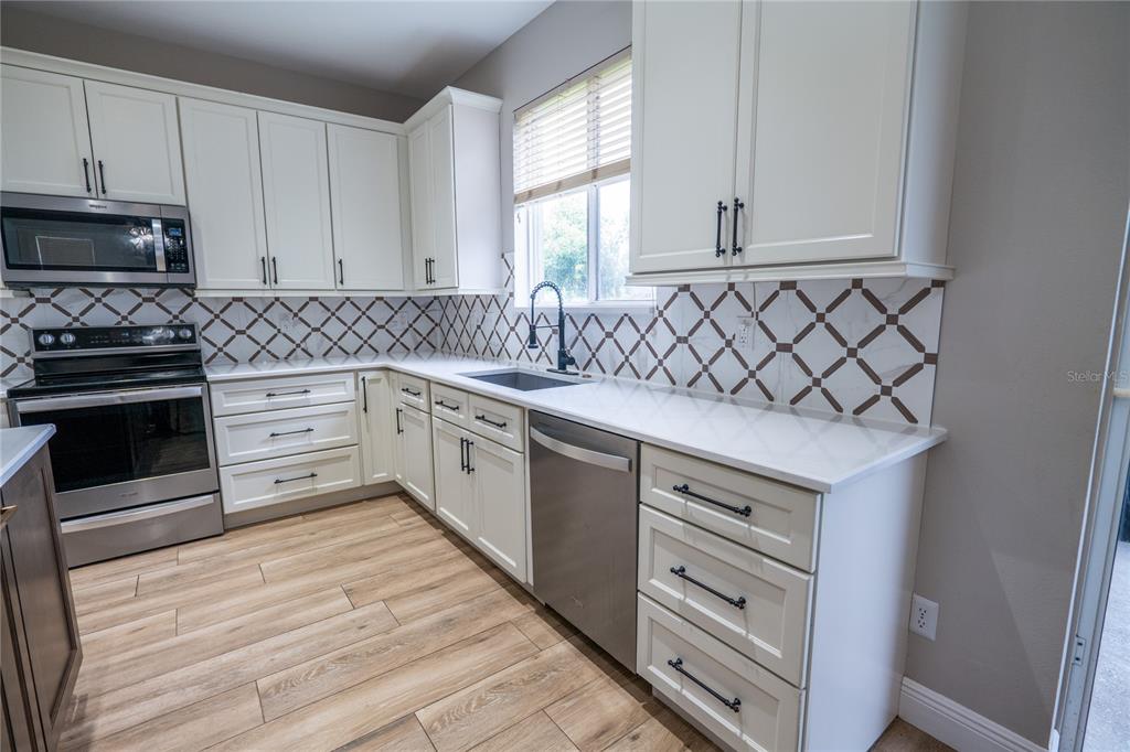 852 North Jacks Lake Road Clermont, FL 34711 - Photo 10 of 29 a kitchen with stainless steel appliances granite countertop a stove a sink and a microwave