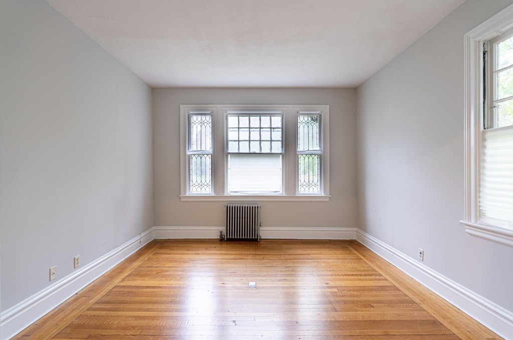 85 Naples Road Brookline, MA 02446 - Photo 6 of 19 an empty room with wooden floor and windows