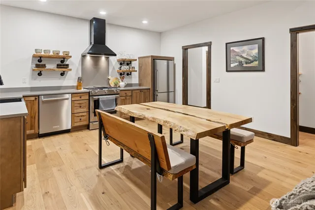 a kitchen with a table chairs refrigerator and wooden floor