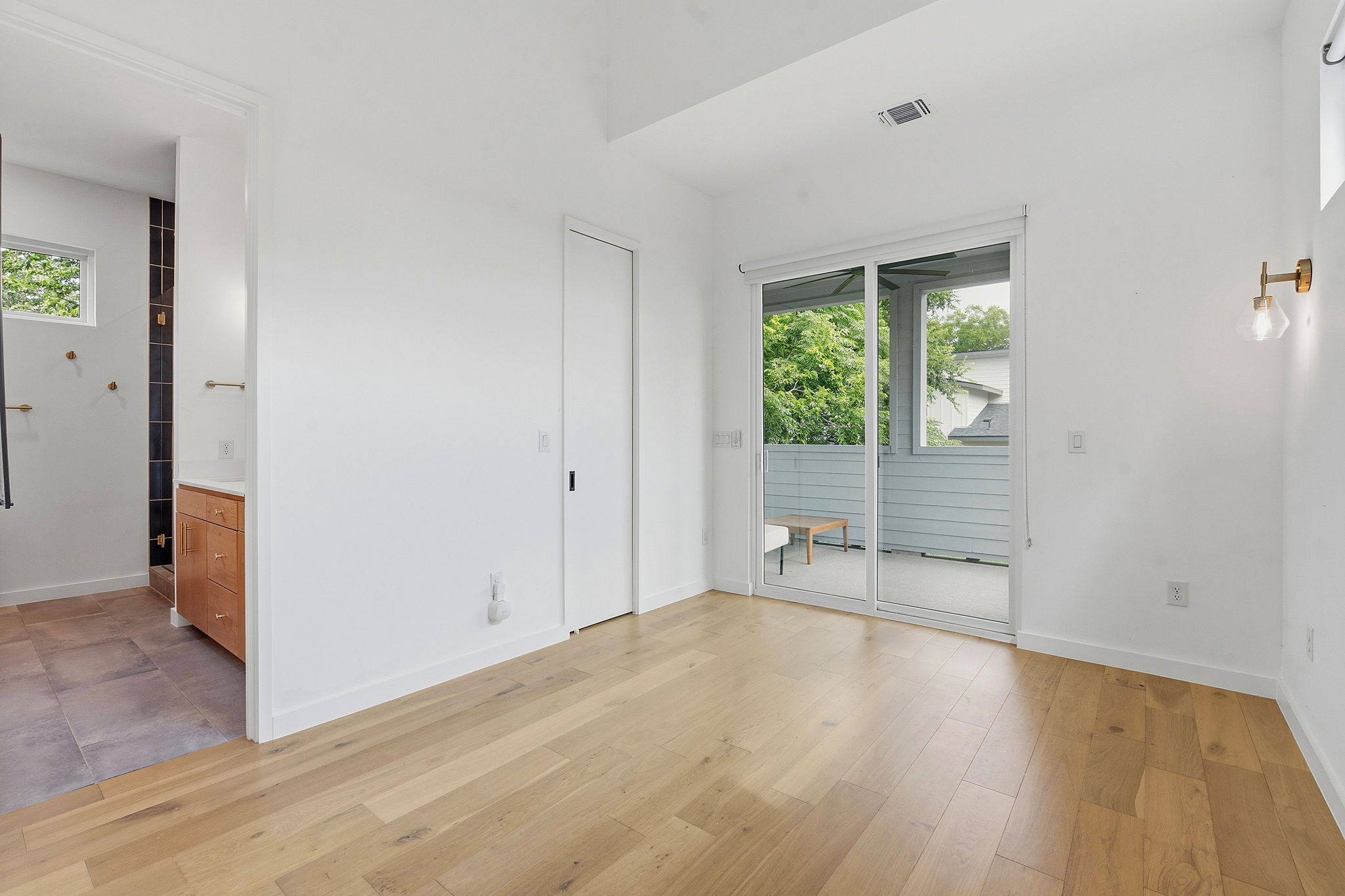 1707 Deloney Street, Unit 2 Austin, TX 78721 - Photo 13 of 26 Blonde hardwood flooring stretches across this open room with a sliding glass door leading to a private balcony.