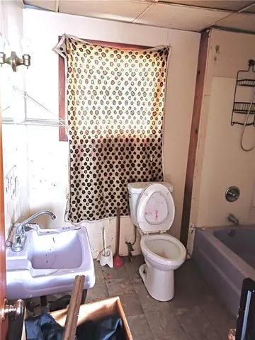 a white toilet sitting next to a bathroom with a sink and toilet