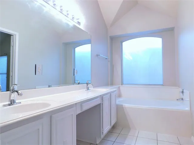 a bathroom with a bathtub a mirror a sink and vanity