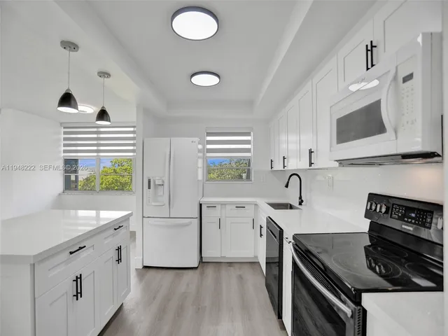 a kitchen with white cabinets and appliances