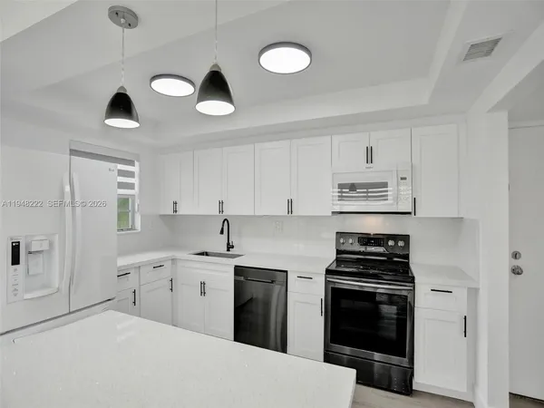 a kitchen with cabinets stainless steel appliances and wooden floor