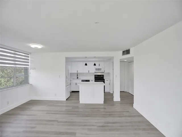 a view of a kitchen with wooden floor and electronic appliances