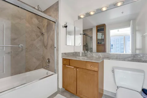 a bathroom with a granite countertop sink a toilet a mirror and shower