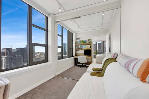 a bedroom with a bed couch and large window