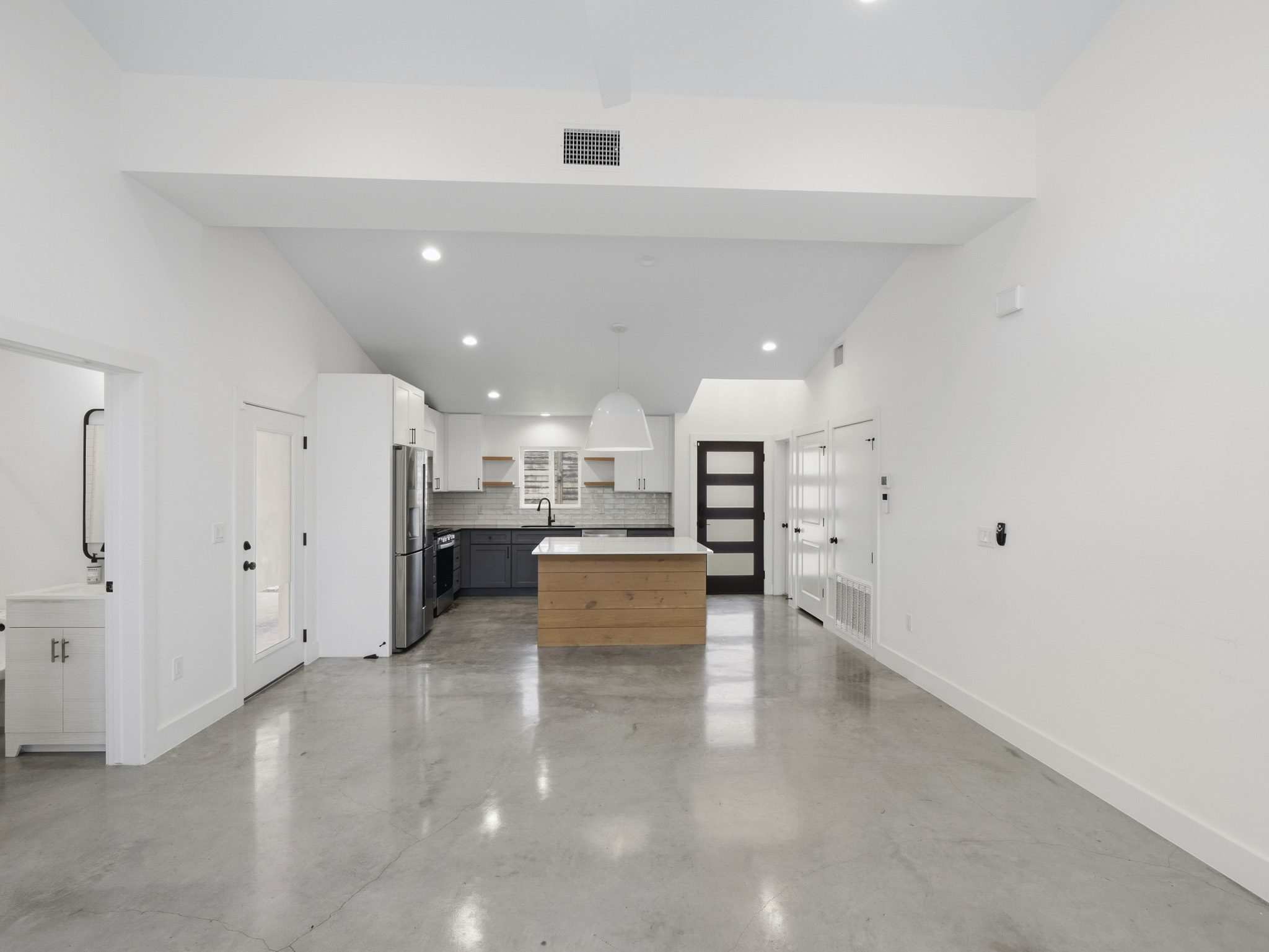 5005 Lott Avenue, Unit 2 Austin, TX 78721 - Photo 8 of 25 A contemporary kitchen and living area with polished concrete floors and a central island.