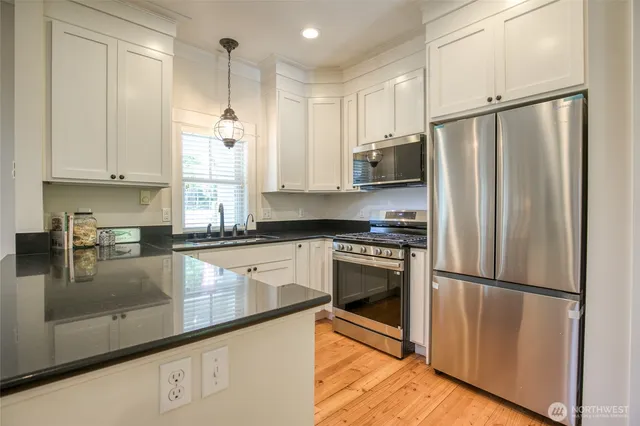 a kitchen with stainless steel appliances granite countertop a refrigerator a sink and white cabinets