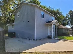 a view of a house that has a small yard and large trees