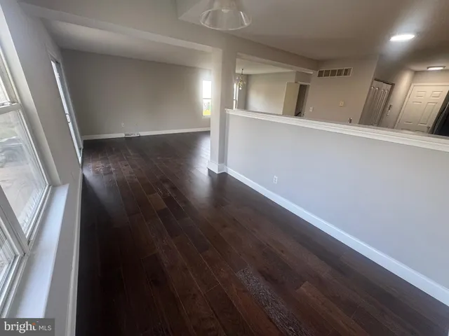 a view of a hallway with wooden floor and a window