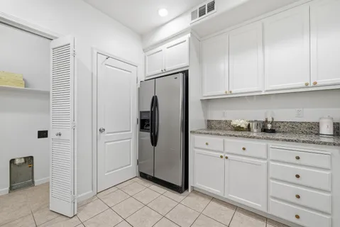 a kitchen with granite countertop white cabinets and refrigerator