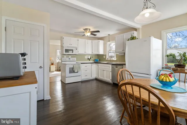 a kitchen with stainless steel appliances kitchen island granite countertop a refrigerator a stove a sink dishwasher and white cabinets with wooden floor