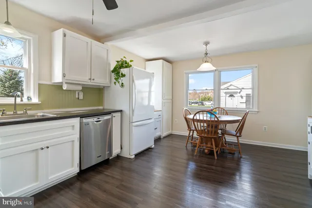 a kitchen with stainless steel appliances granite countertop white cabinets a dining table and chairs