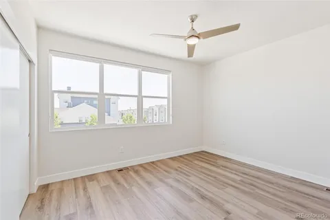 an empty room with wooden floor fan and windows