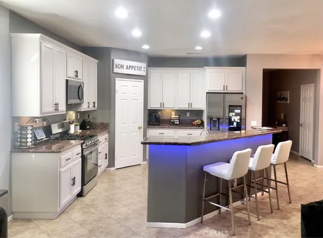 a kitchen with stainless steel appliances granite countertop a stove top oven a sink dishwasher a dining table and chairs