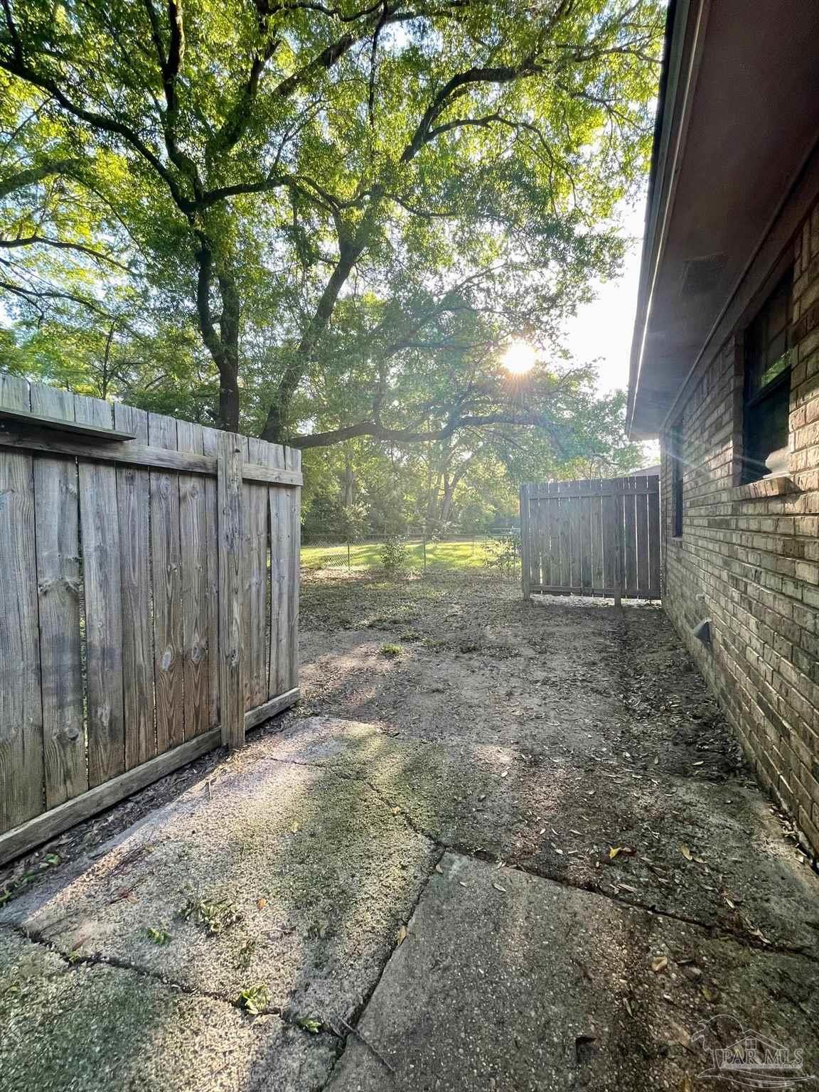 6455 Maddox Road Milton, FL 32570 - Photo 11 of 13 a view of a backyard with large trees and wooden fence