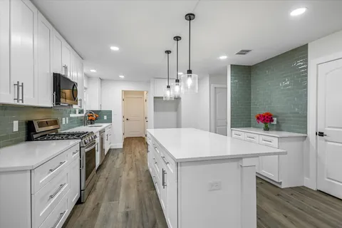 a kitchen with stainless steel appliances kitchen island granite countertop a sink and a refrigerator