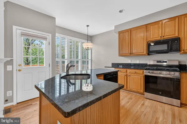 a kitchen with stainless steel appliances granite countertop a stove a sink dishwasher and cabinets with wooden floor
