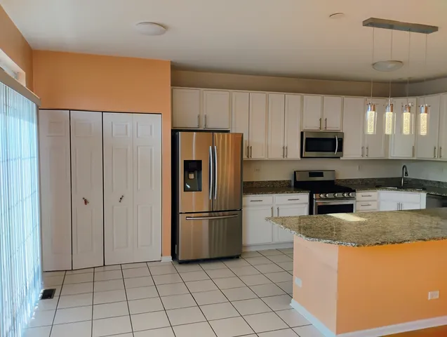 a kitchen with granite countertop a refrigerator and a stove top oven
