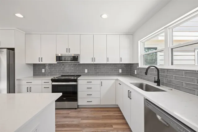 a kitchen with a sink a stove a refrigerator a center island and cabinets