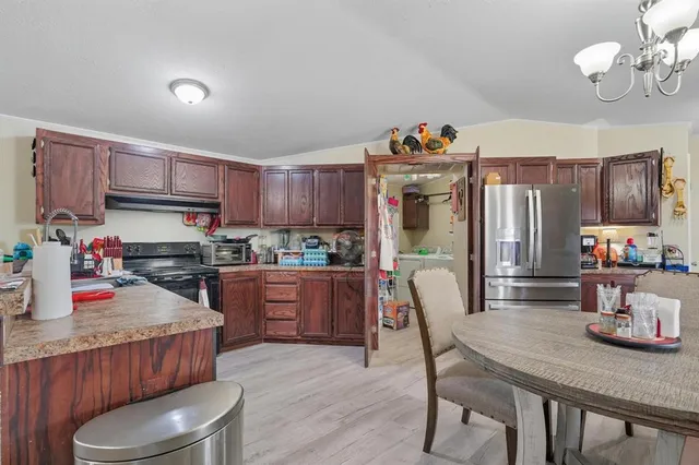 a kitchen with stainless steel appliances granite countertop a refrigerator a stove top oven a sink dishwasher and wooden cabinets with wooden floor