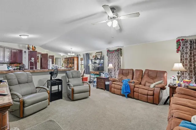 a living room with furniture kitchen view and a chandelier