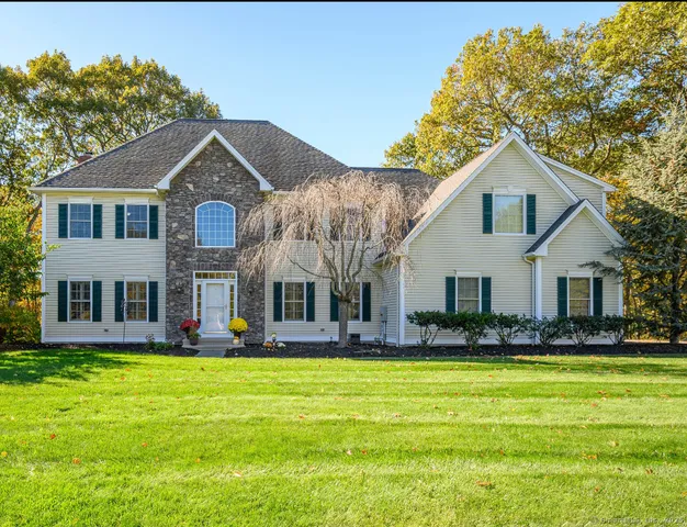 a front view of house with yard and trees in the background