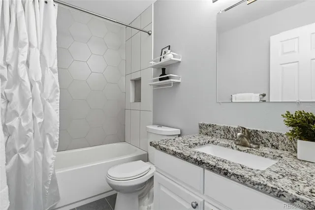 a bathroom with a granite countertop sink a toilet and bathtub